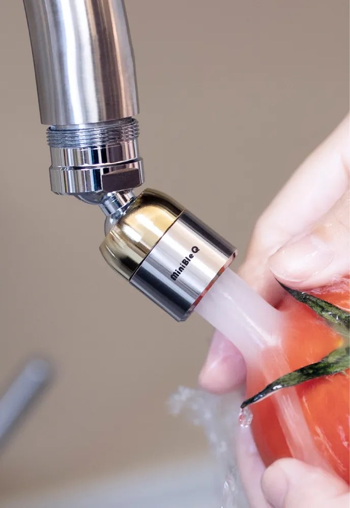 MiniBle Q microbubble generator washing fresh tomatoes under a kitchen faucet